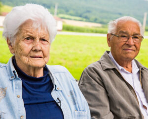 Elderly couple sits outside together at farm