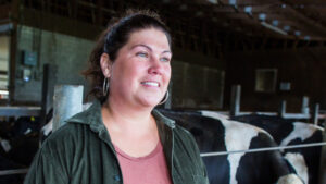 Female dairy farmer smiling in front of cows