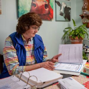 Woman sitting at table reading through binders of documents
