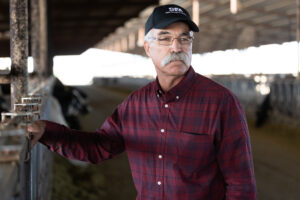 Framer with glasses and hat looks at his barn