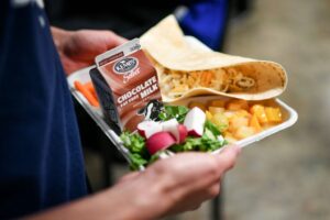 Child carries school lunch with chocolate milk and taco