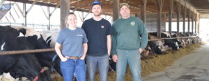 Smiling dairy farmers with cows in the barn