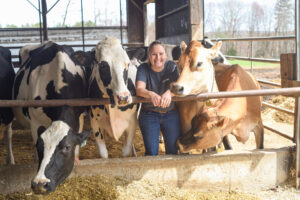 Girl stands between cows smiling