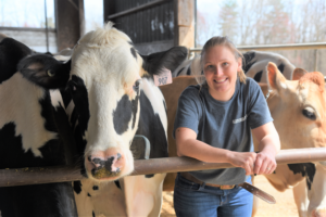 Blonde girl smiling next to cows