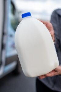 Person holding gallon of milk