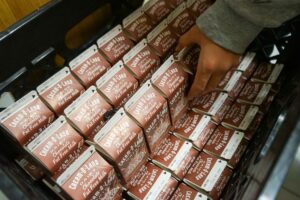 Person grabbing a carton of chocolate milk from a diaplay